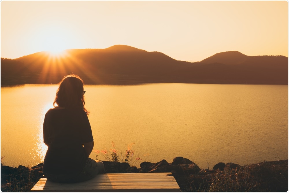 Woman looking out across water and mountains