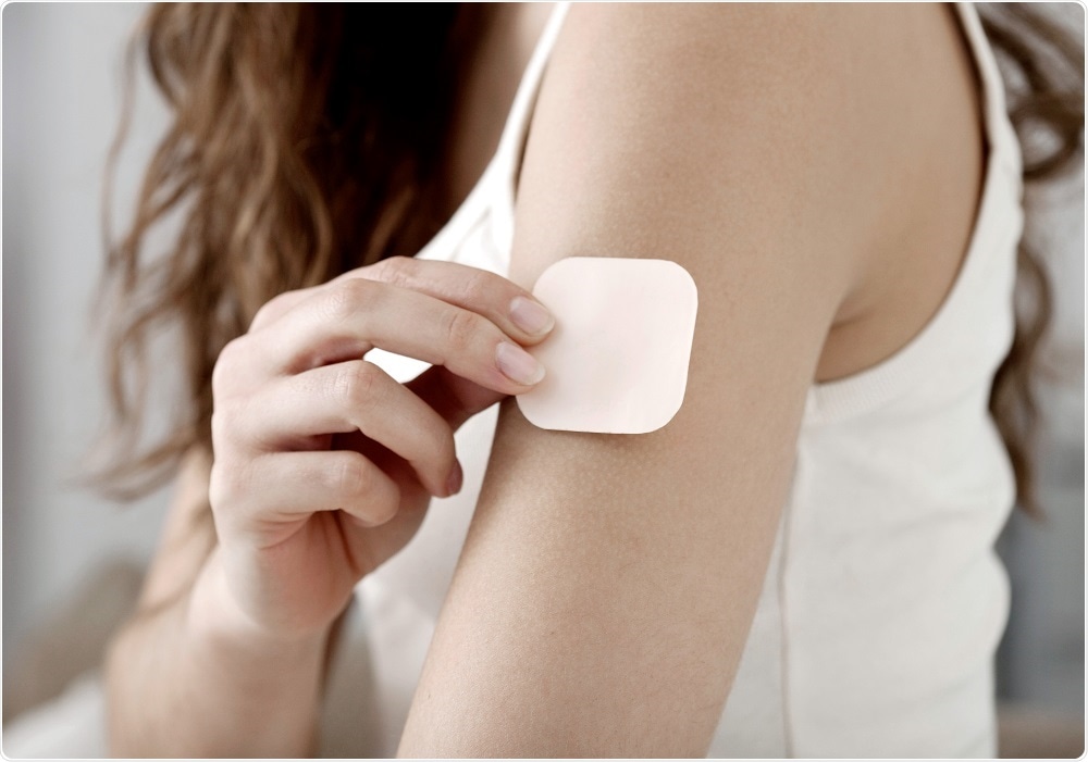 Woman applying contraceptive patch to arm - By Image Point Fr