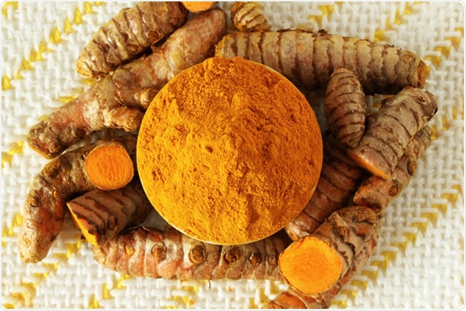 Turmeric or curcumin longa root powder and root. Image Credit: By Govindji / Shutterstock