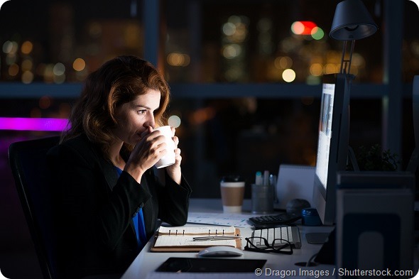 Business woman drinking coffee to get some energy for working overtime