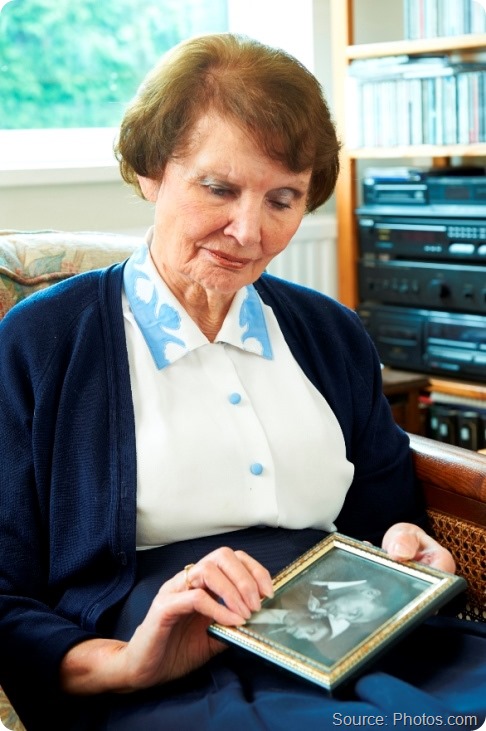 Senior Woman looking sadly at old wedding photograph