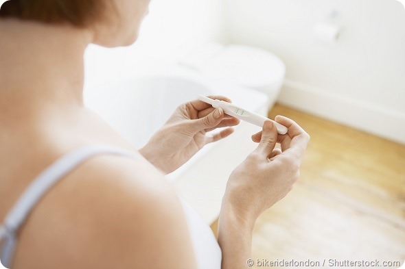 Young woman checking pregnancy test kit in bathroom