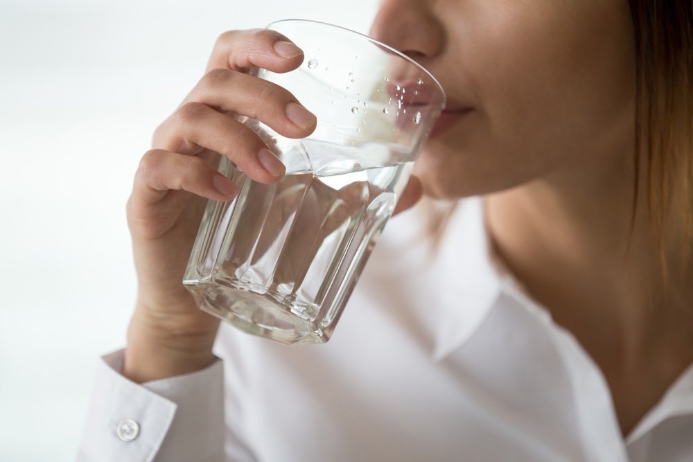 Dehydrated woman feeling thirsty holding glass drinking filtered pure mineral fresh water for body refreshment or energy recovery, dehydration problem, hydration and health concept, close up view. Image Credit: fizkes/Shutterstock.com
