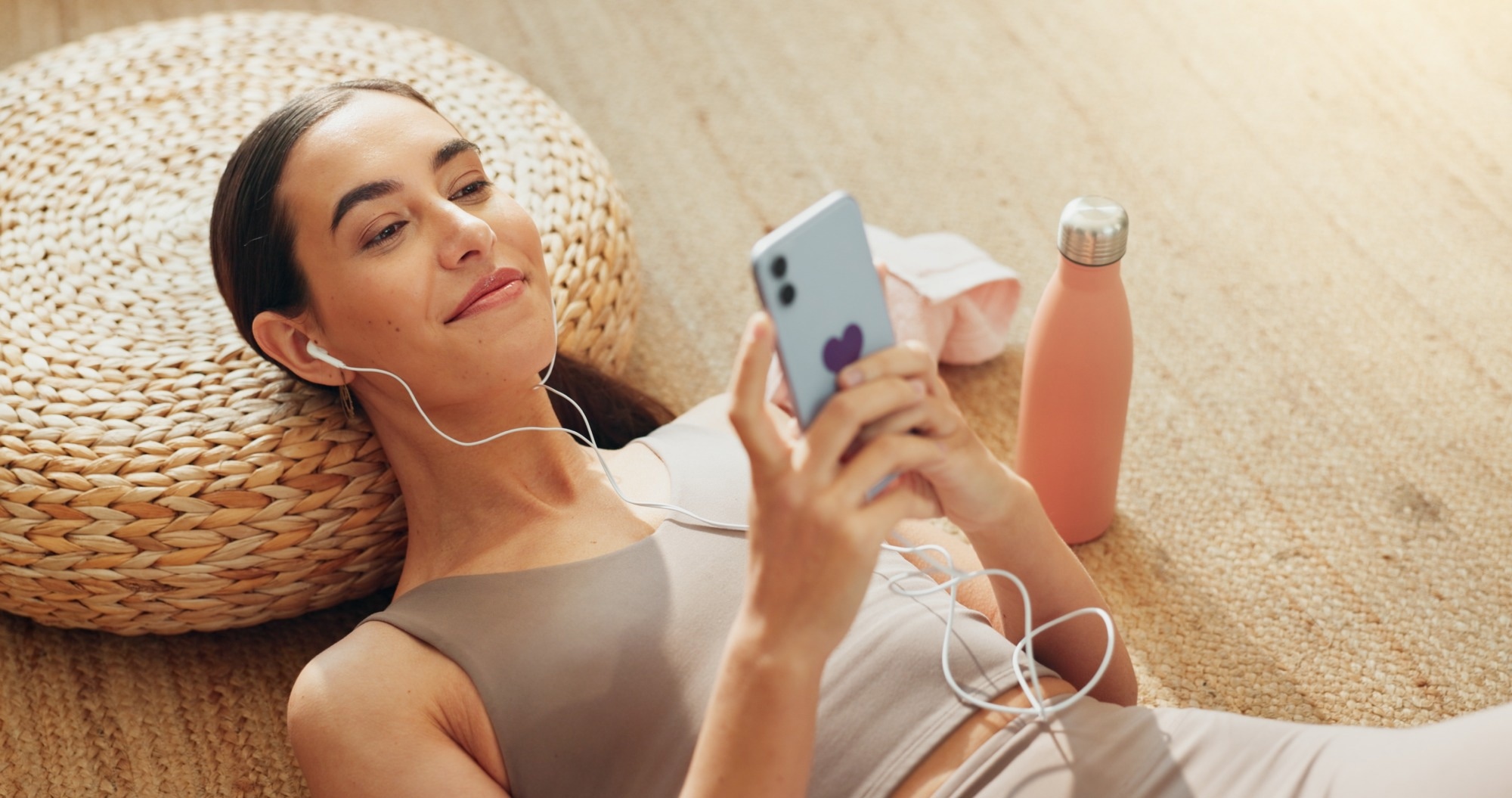 Streaming, phone and relax with woman in home gym for music, exercise podcast and peace.