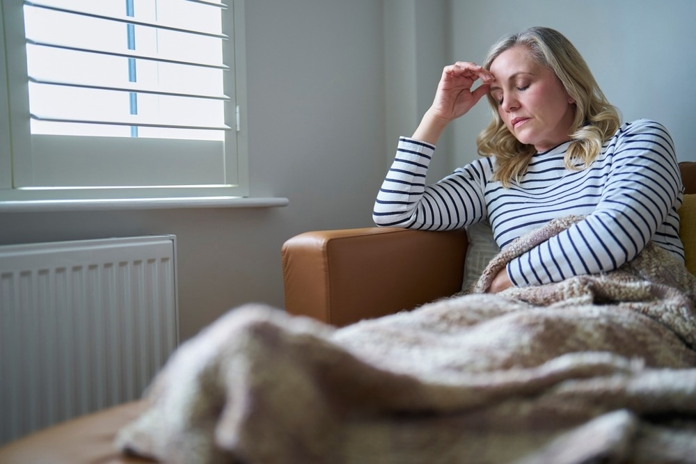 Woman Suffering With Long Term Illness Sitting On Sofa At Home