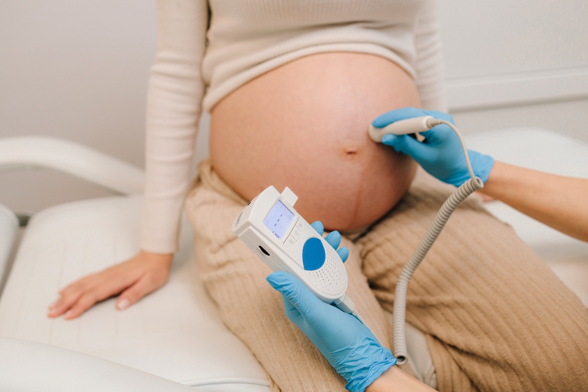 Gynecologist listens to fetus heartbeat with fetal doppler in the clinic.