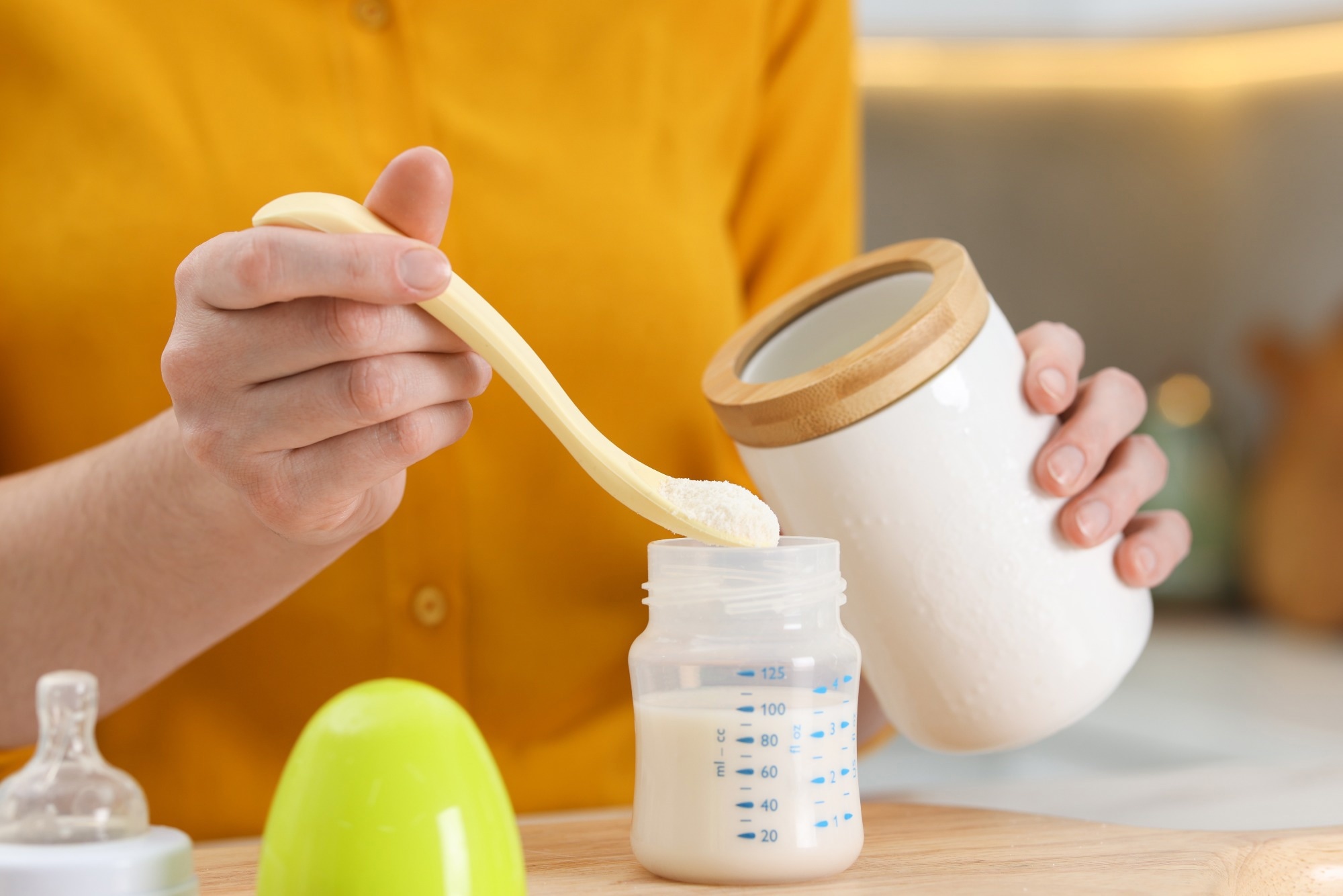Mother making baby formula in feeding bottle