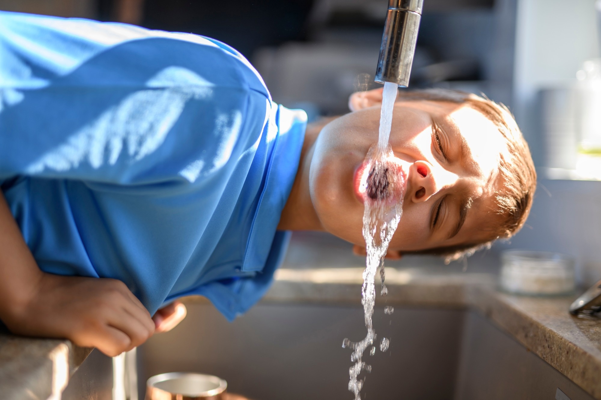 A Boy drinking water direct from the faucet